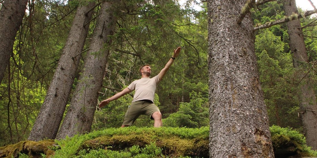 Mann im Wald in der Pose des friedvollen Kriegers