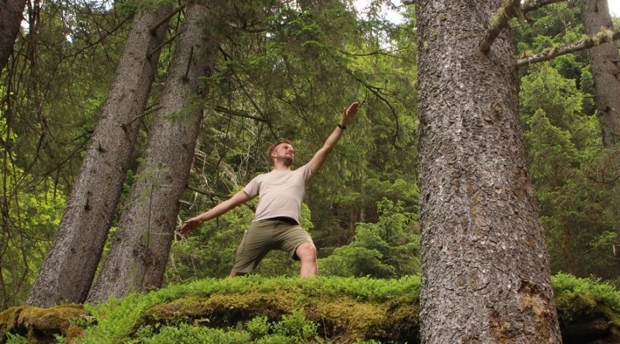 Mann im Wald in der Pose des friedvollen Kriegers