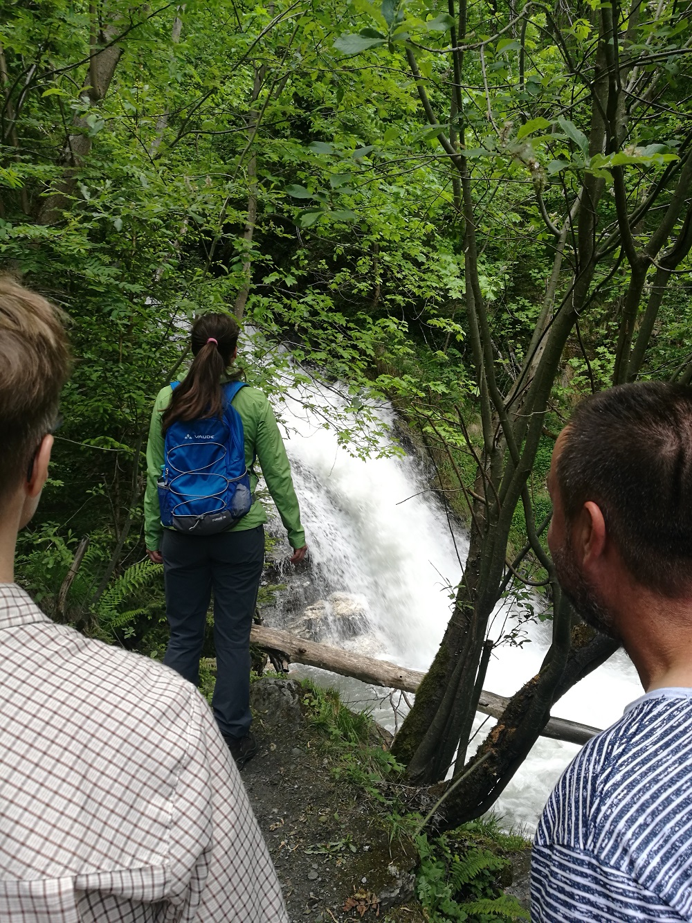 drei Personen beobachten einen Wasserfall