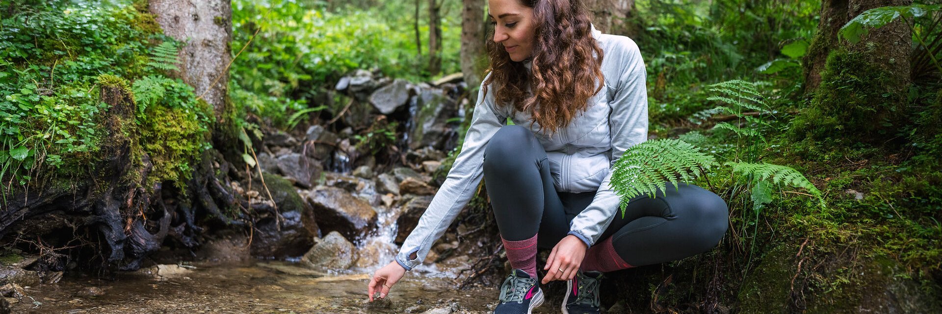 Eine Frau schöpft im Sommer Wasser aus einem klaren und kühlen Gebirgsbach Angertal in Gastein.