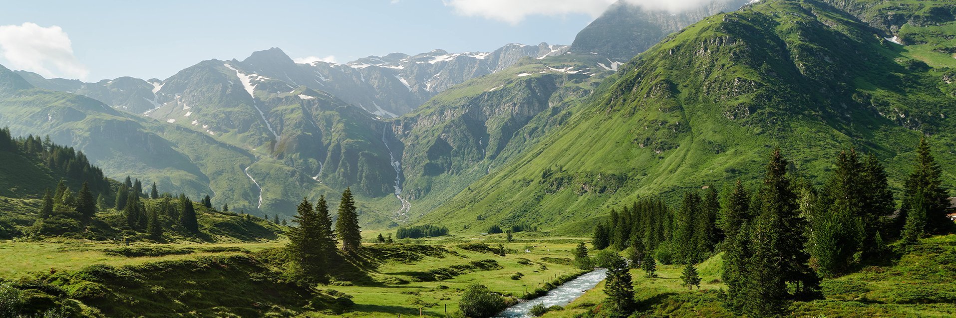 Weiter Blick in das grüne Sportgastein im Sommer umgeben von den Hohen Tauern