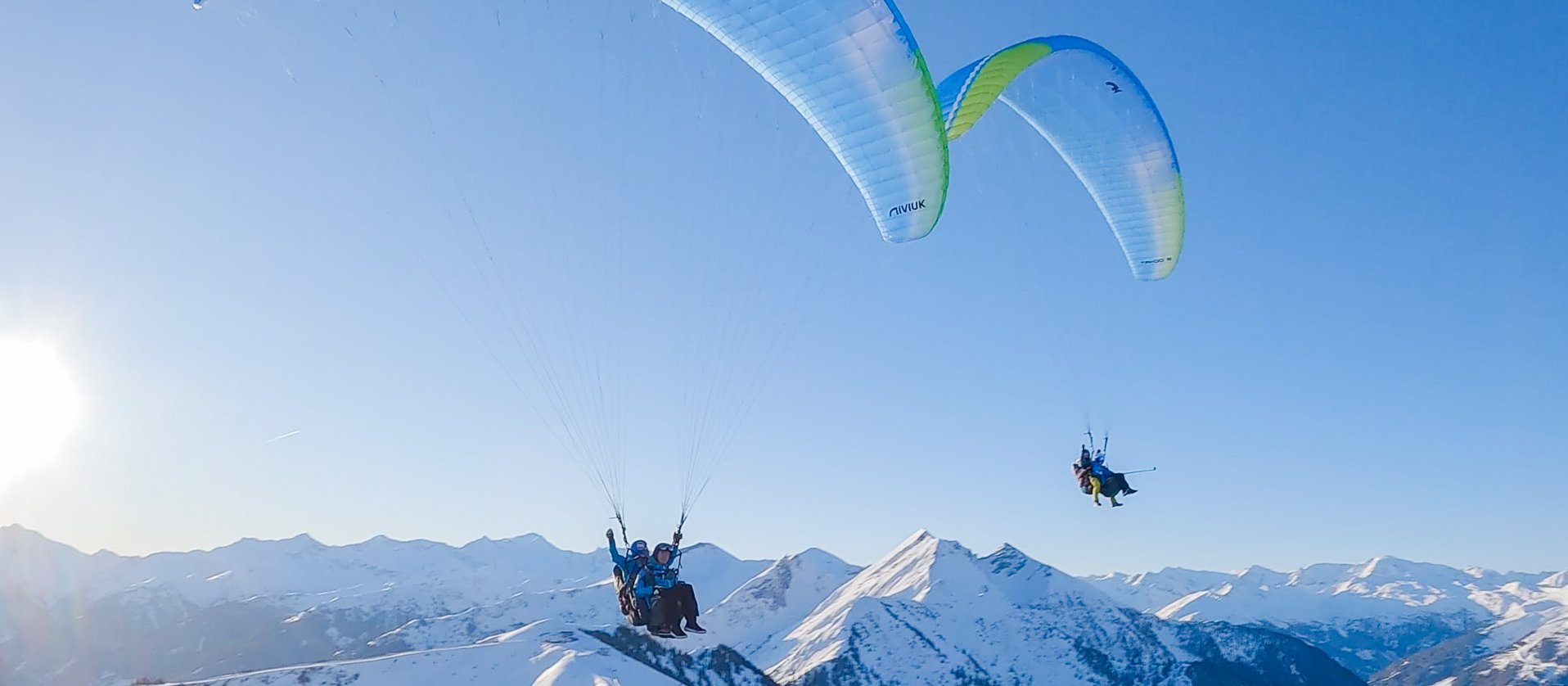 Zwei Paragleiter über den verschneiten Bergen