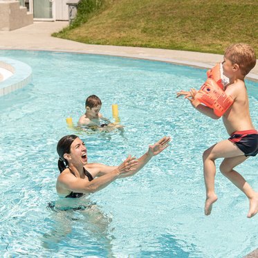 Kind springt ins Becken im Solarbad