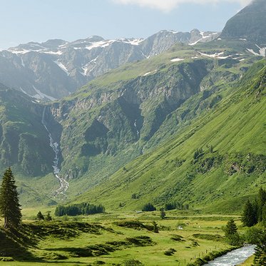 Weiter Blick in das grüne Sportgastein im Sommer umgeben von den Hohen Tauern