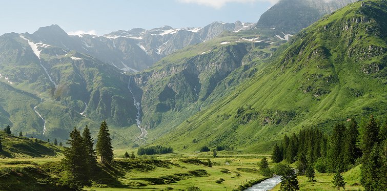 Weiter Blick in das grüne Sportgastein im Sommer umgeben von den Hohen Tauern