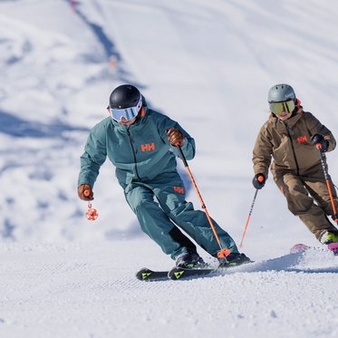 Skifahrer und Skifahrerin beim Carven auf der Schlossalm im Gasteinertal auf frisch präparierter Piste