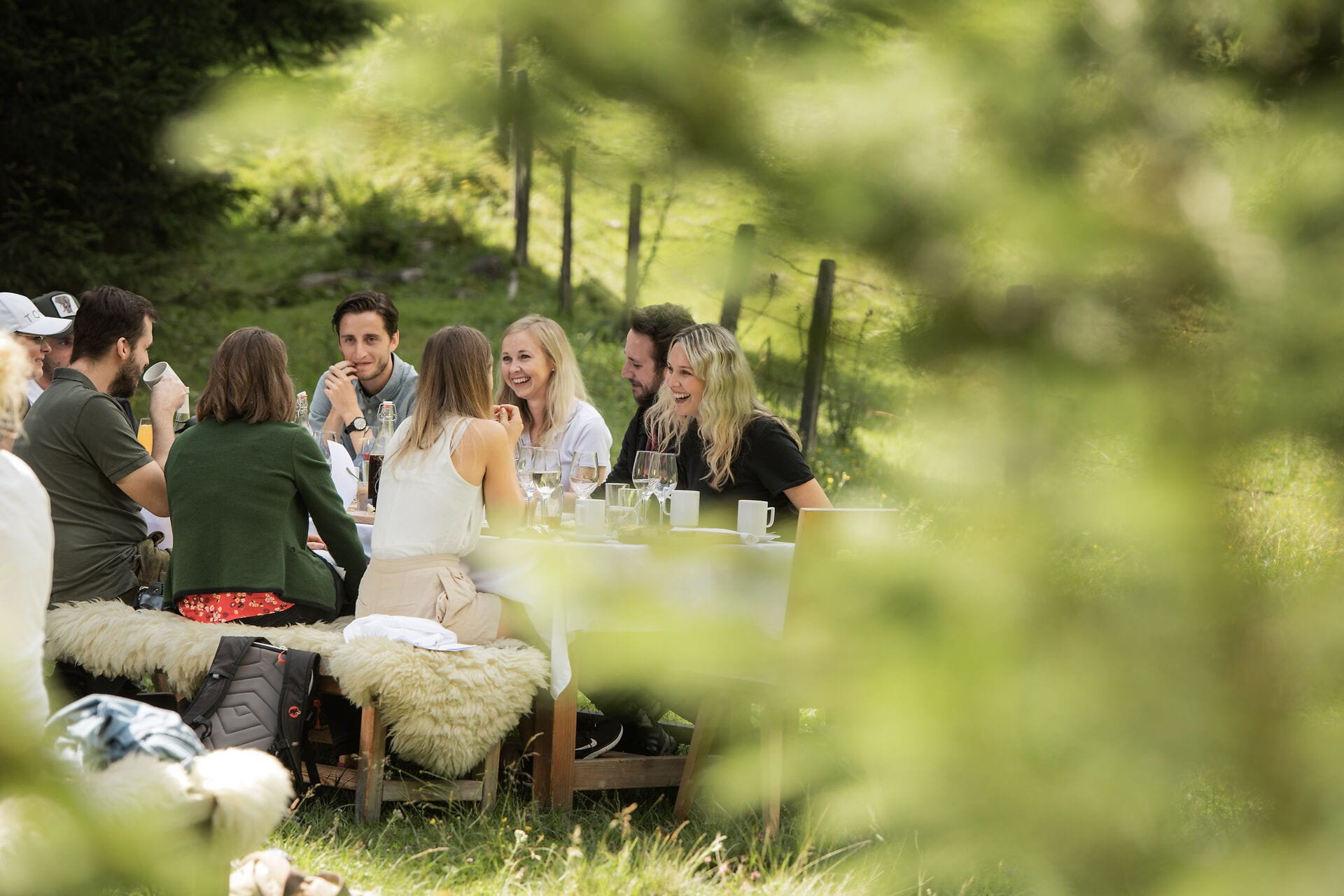 Freunde genießen eine entspannte Zeit im Freien, während sie an einem Tisch mit Essen und Getränken plaudern.
