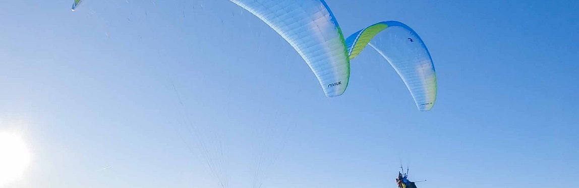 Zwei Paragleiter über den verschneiten Bergen