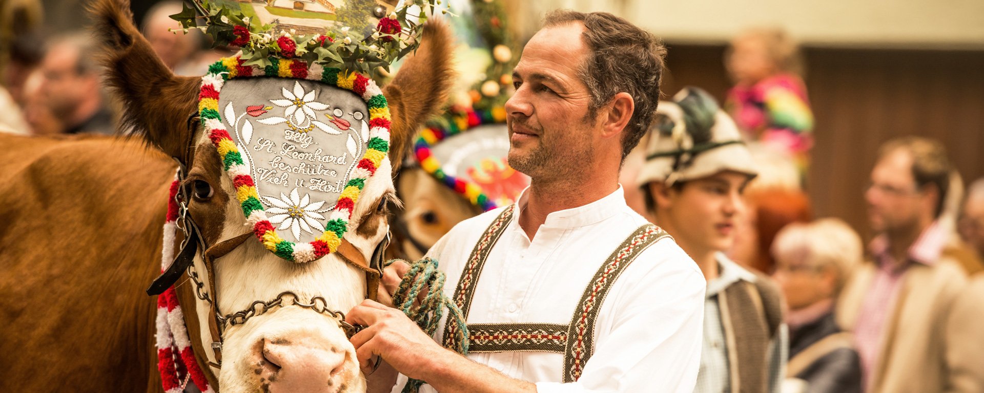 Mann in Tracht mit Pferd, welches einen Kopfschmuck trägt