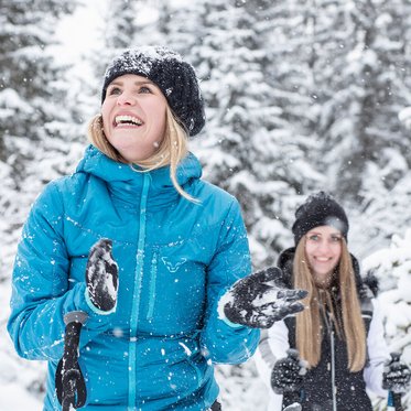 Zwei Frauen genießen im Winter den tiefverschneiten Wald im Angertal in Gastein  bei Schneeschuhwandern.