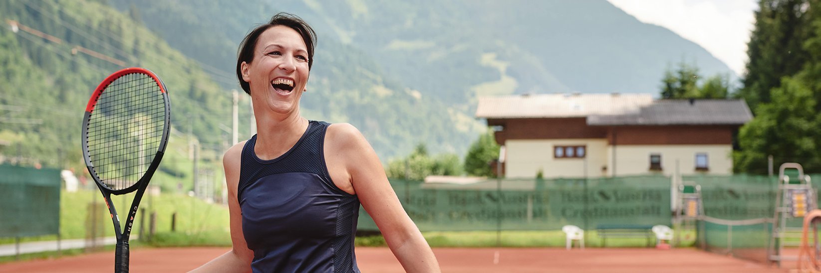 Lachende Frau beim Tennis in Gastein