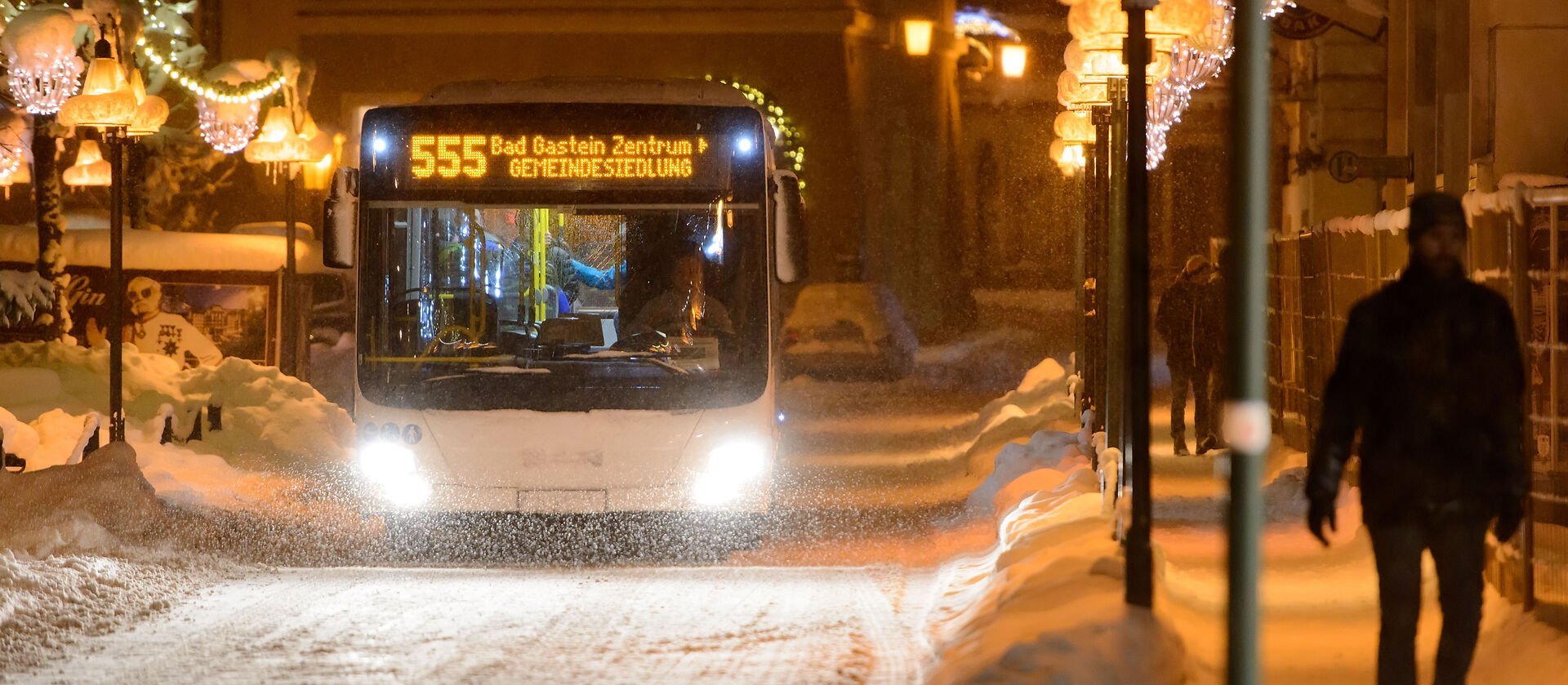 Der Citybus fährt bei Schneefall durch das abendliche Bad Gastein