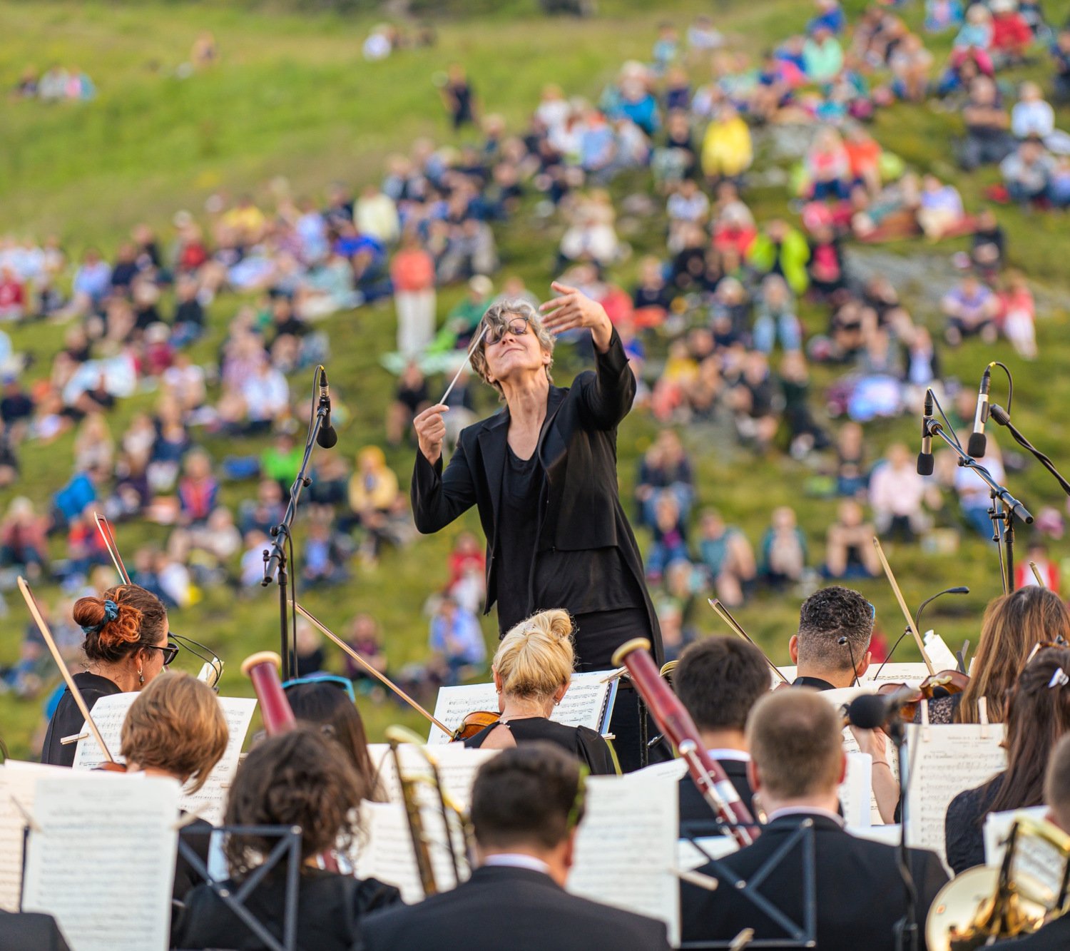 Konzert eines Orchesters bei einem Open-Air-Musikfestival in den Bergen des Gasteinertals mit Publikum auf grünen Almwiesen.