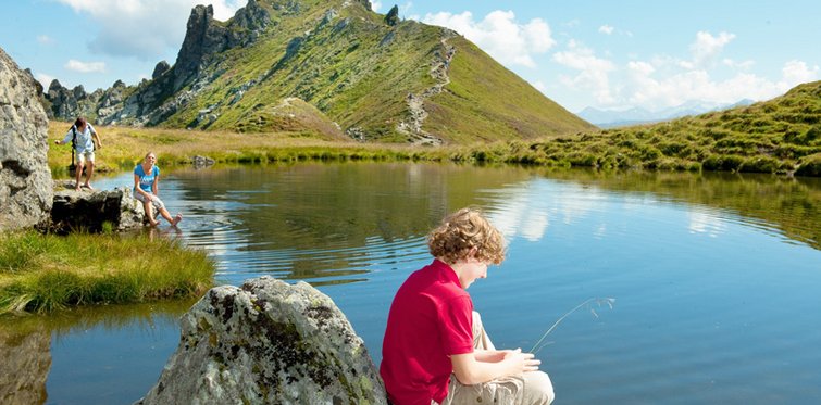 Wanderer auf der Schlossalm in Bad Hofgastein beim Pausieren am Bergsee