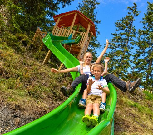 Kinder rutschen die Rutsche im Waldspielplatz
