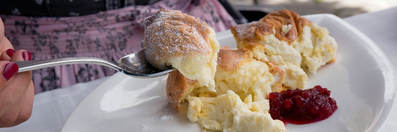 Die berühmte Speise Salzburger Nockerl, jemand mit einer Gabel holt sich bereits ein Stück. 