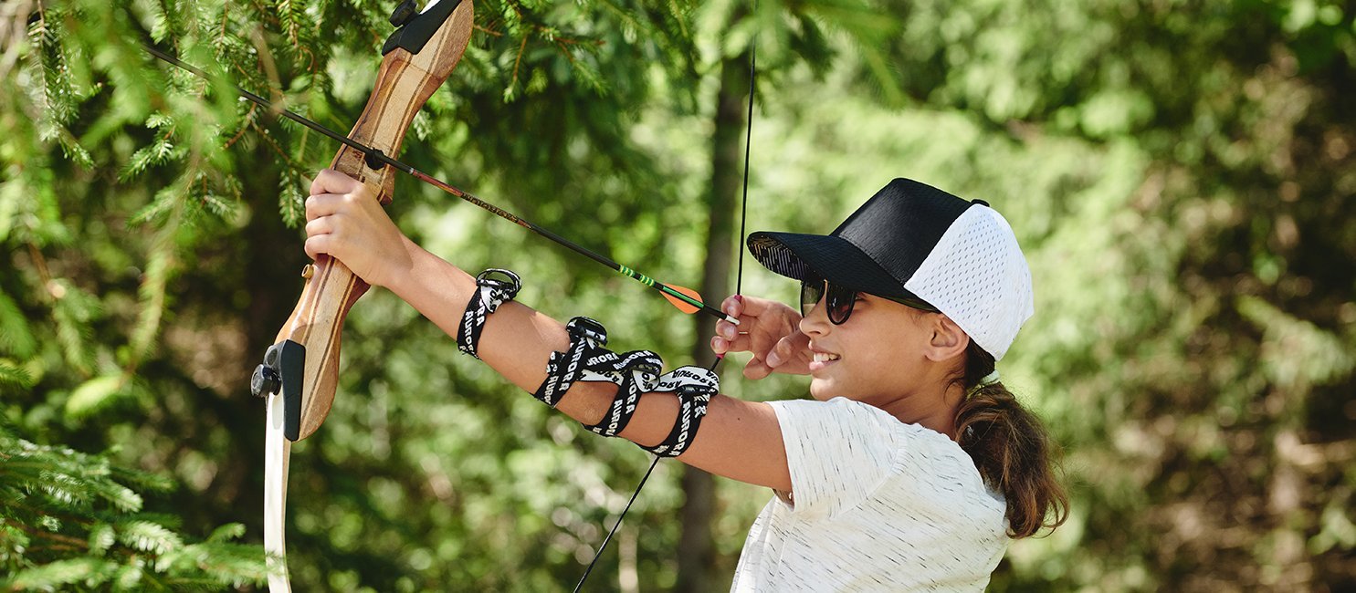 Kind zielt mit Pfeil und Bogen beim Bogenschießen im Gasteinertal.