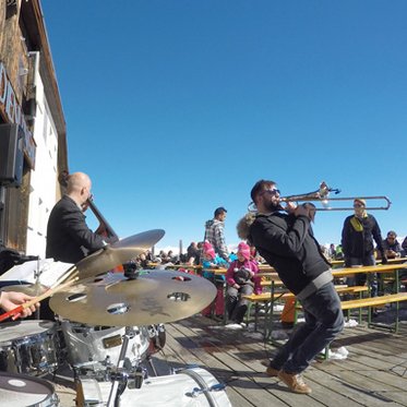 Snow Jazz Gastein Jazzmusiker auf der Terrasse einer Skihütte vor Publikum auf Bierbänken