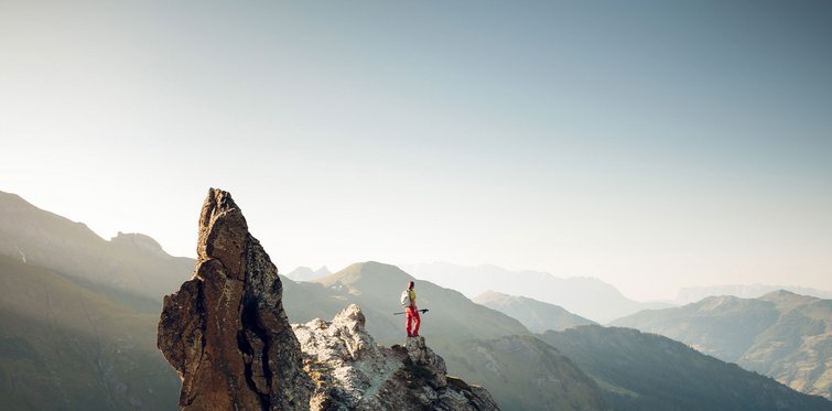 Wanderer steht auf schmalem Felsgrat mit Blick auf die Berglandschaft im Gasteinertal