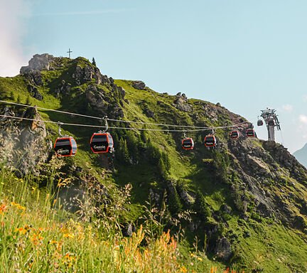 Gondeln der Schlossalmbahn über blühenden Almwiesen auf der Schlossalm in Bad Hofgastein.